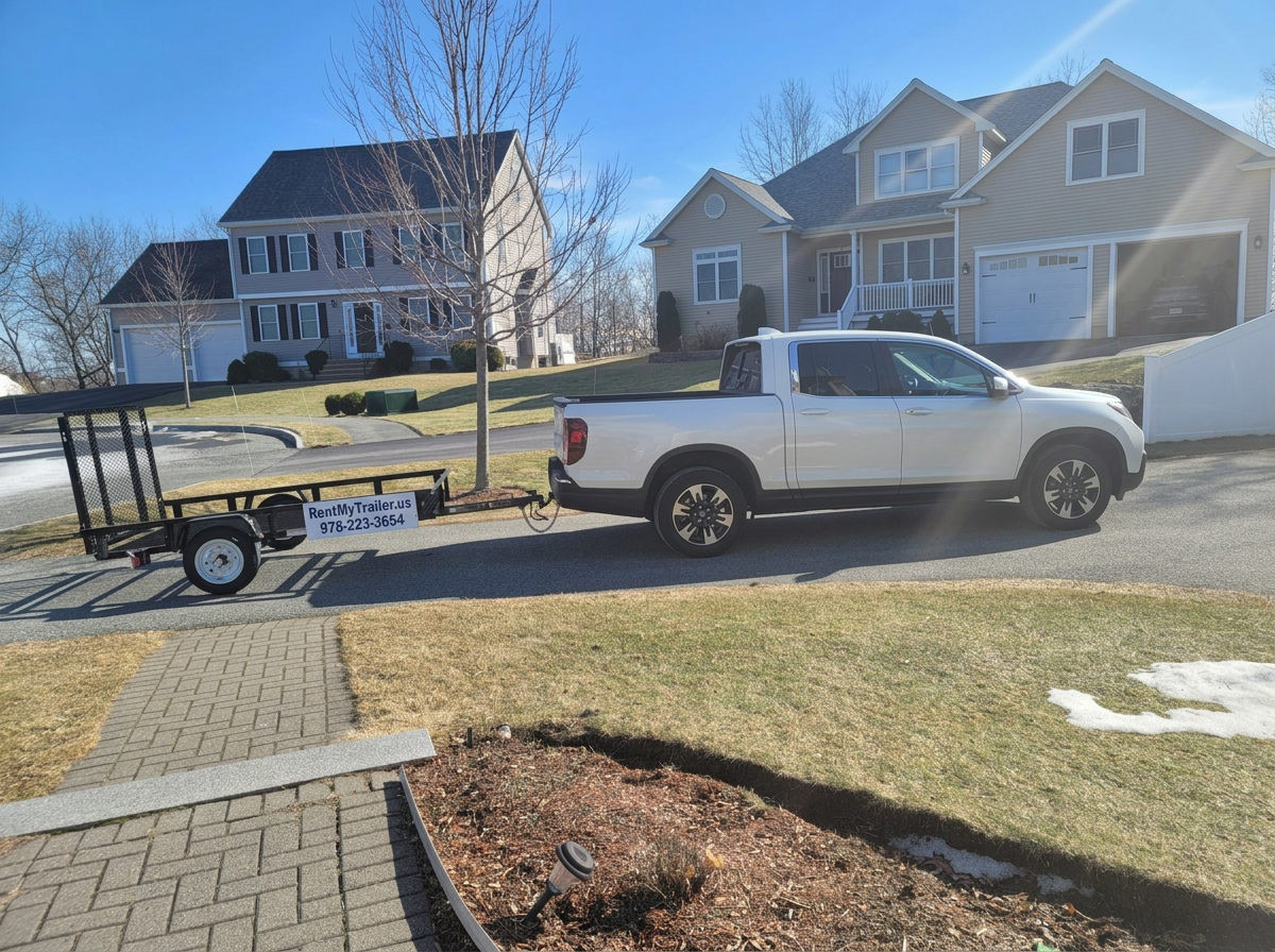 Black utility trailer with RentMyTrailer.us signage towed behind a pickup truck